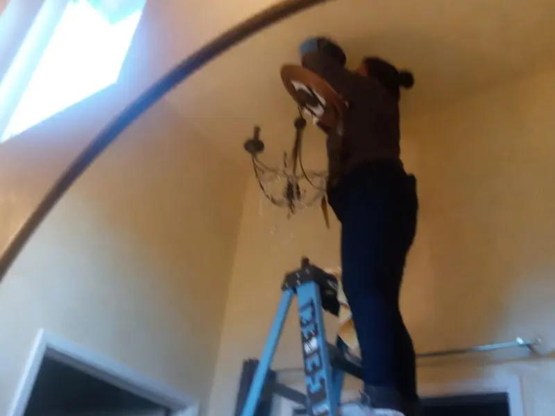 Electrician installing a chandelier in a Woodward residence